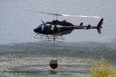 A helicopter with a water bucket dips into Rockport Reservoir to drop water on hot spots about two miles to the south of the wildfire that started Tuesday and destroyed a dozen homes in the Rockport Estates in Wanship, Utah. Helicopters flew hundreds of water drops to fight the fire. The lightning-sparked blaze was among several in the West where fires have devoured dry grass and brush and burned to the edges of small communities. (AP Photo/The Salt Lake Tribune, Al Hartmann) DESERET NEWS OUT; LOCAL TV OUT; MAGS OUT