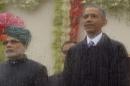India's Prime Minister Modi and U.S. President Obama watch India's Republic Day parade from behind rain streaked bullet proof glass as they stand in the rain together in New Delhi