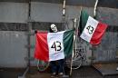 A masked man holds a Mexican flag with the number 43 on it during a protest in Mexico city, on September 26, 2015, to commemorate the first anniversary of the disappearance of 43 students from Ayotzinapa