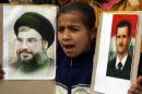 A Lebanese girl holds portraits of Hassan Nasrallah (L), the head of Lebanon's militant Shiite Muslim movement Hezbollah, and Syria's President Bashar al-Assad during a protest near Lebanon's southern village of Marjayoun on March 18, 2014