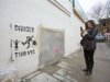 A woman takes a photograph of the former site of "Banksy: Slave Labour", a mural attributed to graffiti artist Banksy, in north London