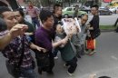 A plainclothes police officer tries to remove a woman away from the area in front of the Chengdu Intermediate People's Court, the location of Wang Lijun's trial, as she protests for personal reasons in Chengdu
