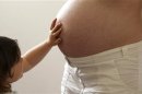 A child touches her pregnant mother's stomach at the last stages of her pregnancy in Bordeaux