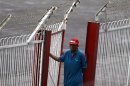 A security personnel wears a cap bearing the brand of Digicel as he mans a gate at a soccer match at Aung San stadium in Yangon