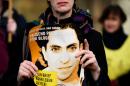 An Amnesty International activist holds a picture of Saudi blogger Raif Badawi during a protest against his flogging punishment on January 29, 2015 in front of Saudi Arabia's embassy to Germany in Berlin