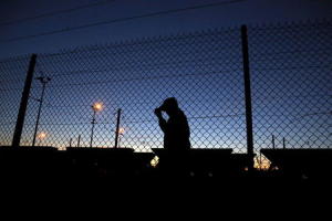 An African migrant walks after crossing the fence as he attempt to access the Channel Tunnel in Frethun, near Calais