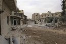 A view shows damaged buildings and a vehicle on a deserted street in Deraa