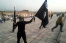 File photo of a fighter of ISIL holding a flag and a weapon on a street in Mosul