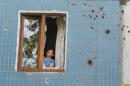 A local woman works on her window after shelling in Donetsk, eastern Ukraine, Friday, Aug. 8, 2014. At least three civilians have been killed and another 10 wounded in overnight shelling of the main rebel stronghold in eastern Ukraine besieged by government forces, officials said. (AP Photo/Sergei Grits)