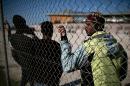 Migrants from Somalia stand behind a fence outside a temporary housing facility for migrants located in a former Olympic hall in Faliro suburb of Athens, on December 13, 2015