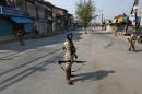 Indian policemen stand guard in a deserted street during a curfew in Srinagar