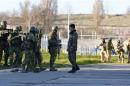 A Ukrainian serviceman talks to armed men, believed to be Russian servicemen, who stand guard at a military airbase, in the Crimean town of Belbek near Sevastopol
