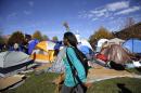 A woman passes a tent encampment set up by student protesters following an announcement that University of Missouri System President Tim Wolfe is resigning Monday, Nov. 9, 2015, at the university in Columbia, Mo. Wolfe resigned Monday with the football team and others on campus in open revolt over his handling of racial tensions at the school. (AP Photo/Jeff Roberson)