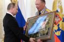 In this pool photo taken on Thursday, March 17, 2016, Russian President Vladimir Putin, left, receives a picture taken in Syria from Col. Gen. Alexander Dvornikov during an awarding ceremony in Moscow's Kremlin, Russia. Dvornikov, who commanded the Russian military in Syria, said in an interview released Wednesday that Russia's special forces have helped direct air raids in Syria and Russian military advisers have played a key role in the Syrian army's offensive.(Alexei Nikolsky/Sputnik, Kremlin Pool Photo via AP)