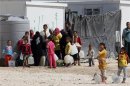 Syrian refugees wait to collect water at the Al Zaatri refugee camp