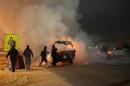 Egyptian firefighters extinguish fire from a vehicle outside a sports stadium in a Cairo's northeast district, on February 8, 2015 during clashes between supporters of Zamalek football club and security forces