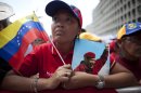 A woman holds a picture of Venezuela's President Hugo Chavez and the country's national flag during an event commemorating the violent street protests of 1989 known as the "Caracazo," in Caracas, Venezuela, Wednesday, Feb. 27, 2013. The wave of the 1989 violent protests, seen by the Chavez government as a "popular uprising," was in response to the economic measures imposed by then President Carlos Andres Perez. (AP Photo/Ariana Cubillos)