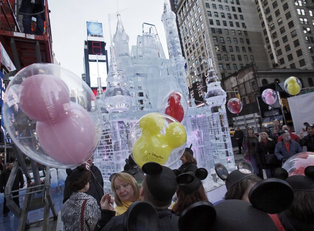 People with mouse ear caps and balloons gather near a three-story castle mad of ice in New York's Times Square, Wednesday, Oct. 17, 2012. On Wednesday, Disney announced a new program for 2013, "Limited Time Magic," in which guests will encounter surprise weekly themes at Disney parks in Florida and California. The program was described as "52 weeks of magical experiences big and small that appear, then disappear as the next special surprise debuts." For example, a weeklong Valentine's Day celebration might include pink lighting on Disney castles, surprise meet-and-greets with Disney characters and candlelit dinners for lovebirds. (AP Photo/Richard Drew)
