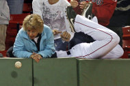 FOR USE AS DESIRED, YEAR END PHOTOS - FILE -In this Sept. 19, 2011 file photo, a fan watches as the baseball drops away as Boston Red Sox left fielder Conor Jackson, right, leaps into the crowd on an unsuccessful attempt to catch a foul ball by Baltimore Orioles' J.J. Hardy in the first inning during the second game of a baseball doubleheader at Fenway Park in Boston. (AP Photo/Charles Krupa, File)