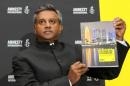 Amnesty International Secretary General Salil Shetty displays a report during a press conference in Doha on November 17, 2013