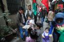 Palestinian refugees living in the Shatila refugee camp in the Lebanese capital of Beirut hand out sweets as they celebrate following the news of the death of former Israeli premier Ariel Sharon, on January 11, 2014