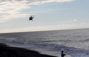 A man fishes from the shore as a French Police helicopter&nbsp;&hellip;