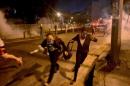Protesters run from tear gas shot by riot police in Rio de Janeiro