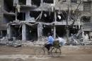 A man rides a bicycle near damaged buildings in Jobar, a suburb of Damascus, Syria
