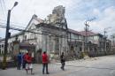 Filipinos stand by a damaged Basilica Del Sto Nino in Cebu, central Philippines Tuesday, Oct. 15, 2013. A 7.2-magnitude earthquake collapsed buildings, cracked roads and toppled the bell tower of the Philippines' oldest church Tuesday morning, killing at least 20 people across the central region. (AP Photo/Chester Baldicantos)