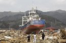 FILE - In this April 2, 2011 file photo, survivors look at a ship among the rubble at a March 11 earthquake and tsunami-destroyed area in Kesennuma, Miyagi prefecture, Japan. The stranded fishing boat that became a symbol of the devastation of Japan's 2011 tsunami has long divided a northeastern coastal city - between those who wanted to keep it as a monument of survival and those who wanted a painful reminder gone. Last week, the city announced it will be torn down after a heated debate and citywide vote. (AP Photo/Lee Jin-man, File)