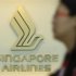 A woman walks past a SIA logo at a ticketing booth at Changi airport in Singapore