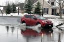 A resident of Bell Tower Condominium Apartments drives through water from a swollen Cayuga Creek as flooding from melting snow following last week's snowstorms are occurring on a minor scale, Monday, Nov. 24, 2014, in Lancaster, N.Y. (AP Photo/Gary Wiepert)