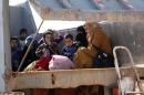 Iraqi women and children, who fled Fallujah, sit in the back of a truck as they wait at an army checkpoint at Ayn al-Tamer crossing at the entrance to Karbala province on January 6, 2014