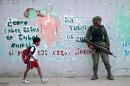 A boy walks past a Mexican soldier as he stands guard outside a school during a security operation following a teacher's strike in Acapulco, Mexico on November 17, 2015
