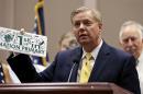 Republican presidential candidate, Sen. Lindsey Graham, R-S.C., holds up a license plate signed by other presidential candidates during a campaign event at city hall in Manchester, N.H., Wednesday, July 15, 2015. (AP Photo/Charles Krupa)