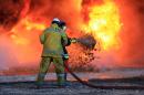 Libyan oil workers try to extinguish flames at an oil facility in northern Libya's Ras Lanouf region after it was set ablaze following fresh attacks launched by Islamic State (IS) group jihadists to seize key port terminals, on January 21, 2016