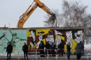 Police officers guard a construction site and sections of the East Side Gallery, while parts of the former Berlin Wall are removed in Berlin, Germany, Wednesday March 27, 2013. Work crews backed by about 250 police have removed portions of the Berlin Wall known as the East Side Gallery to make way for an upscale building project, despite demands by protesters that the site be preserved. Plans to remove part of the 1.3-kilometer (3/4-mile) stretch of wall sparked protests that developers were sacrificing history for profit. (AP Photo/dpa, Britta Pedersen)