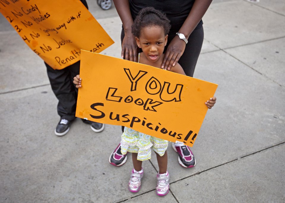 CORRECTS FIRST NAME TO JEDIAH-Jediah Jones, 3, holds a sign as her mother Keiota Jones, stands behind her during a protest the day after George Zimmerman was found not guilty in the 2012 shooting death of teenager Trayvon Martin, Sunday, July 14, 2013, in Atlanta. (AP Photo/David Goldman)