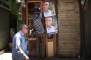 Man hangs posters of presidential candidate Ahmed Shafiq at his shop in Cairo