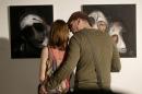 People look at paintings by Syrian artist Majd Kara, who fled his country, in Vilnius, Lithuania