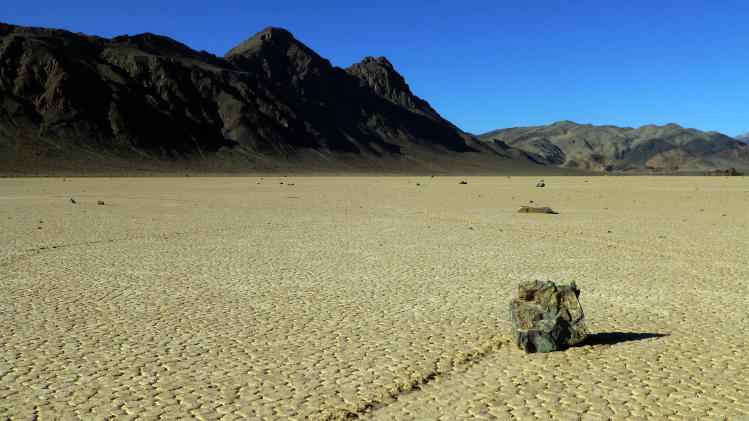 This undated photo provided by the National Park Service shows rocks that have moved across a dry lake bed in Death Valley National Park in California&#39;s Mojave Desert. For years scientists have theorized about how the large rocks — some weighing hundreds of pounds — zigzag across Racetrack Playa leaving long trails etched in the earth. Now two researchers at the Scripps Institution of Oceanography have photographed these &quot;sailing rocks&quot; being blown by light winds across the former lake bed. Cousins Richard Norris and James Norris say the movement is made possible when ice sheets that form after rare overnight rains melt in the rising sun, making the hard ground muddy and slick. (AP Photo/National Park Service)