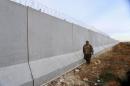 A Kurdish People's Protection Units (YPG) fighter walks near a wall, which activists said was put up by Turkish authorities, on the Syria-Turkish border in the western countryside of Ras al-Ain, Syria