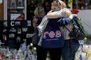 Mourners hug in front of the IV Deli Mart, where part of Friday night's mass shooting took place, on Tuesday, May 27, 2014 in the Isla Vista area near Goleta, Calif. Sheriff's officials said Elliot Rodger, 22, went on a rampage near the University of California, Santa Barbara, stabbing three people to death at his apartment before shooting and killing three more in a crime spree through a nearby neighborhood. (AP Photo/Chris Carlson)