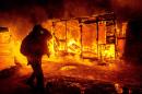 A migrant walks past burning shacks, in the "Jungle" migrant camp, as half of the camp is being dismantled, in Calais on March 1, 2016