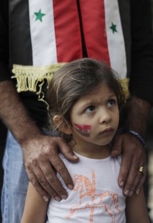 A girl with the Syrian flag painted on her cheek attends …