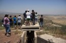Israelis look at the nearby Syrian village of Jebata al-Khashab from an Israeli army post near the village of Buqaata