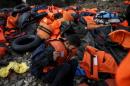 A migrant man rests next to a pile of lifejackets, moments after arriving on a raft on the Greek island of Lesbos
