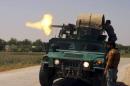 Policemen fire from an armoured vehicle during a battle with Taliban insurgents in Kunduz