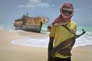 FILE - In this Sunday, Sept. 23, 2012 file photo, masked Somali pirate Hassan stands near a Taiwanese fishing vessel that washed up on shore after the pirates were paid a ransom and released the crew, in the once-bustling pirate den of Hobyo, Somalia. Three Somali pirates were killed in a fight over the ransom paid to free the German-American journalist Michael Scott Moore who was released this week after two years and eight months of captivity, a Somali police official said Friday, Sept. 26, 2014. (AP Photo/Farah Abdi Warsameh, File)