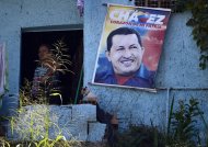 A woman stands near a poster of Venezuelan President Hugo Chavez in Caracas, on January 2, 2013. The head of an opposition umbrella group, the MUD, accused the government of "outlandish irresponsibility" in trying to make it appear that Chavez was exercising his duties as president as he underwent a difficult recovery in Cuba